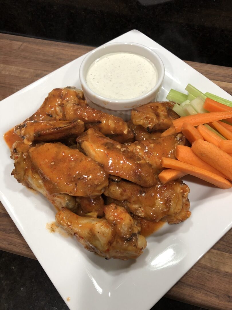 A plate of buffalo chicken wings with celery and carrots.