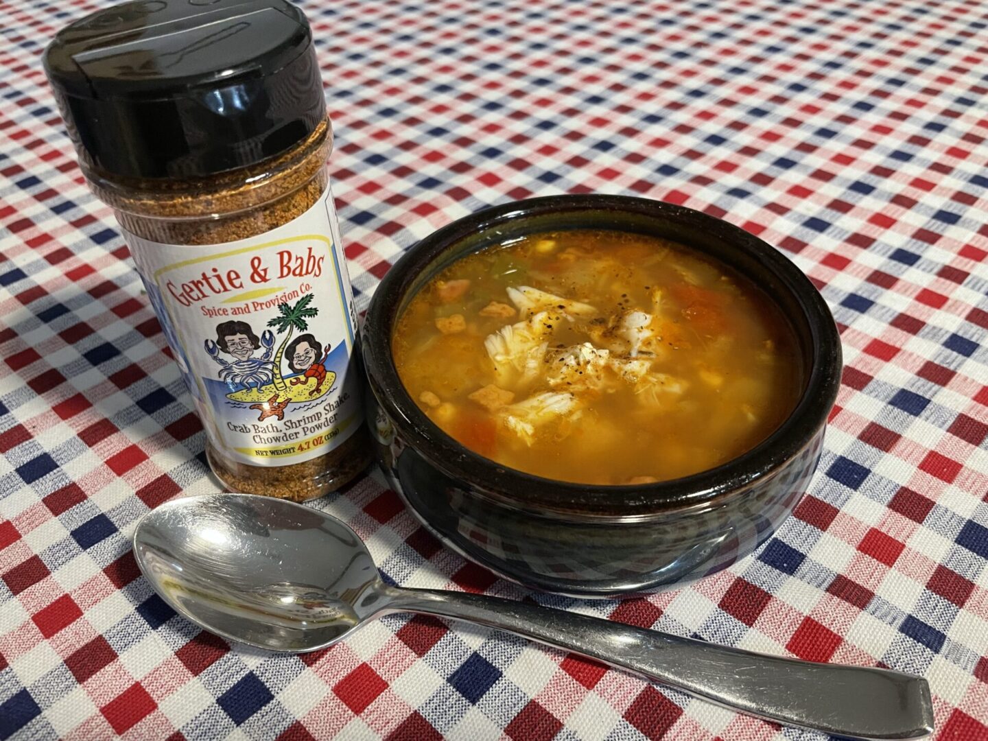 A bowl of seafood chowder with a bottle of seasoning.